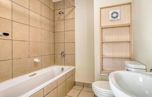 Clean and modern minimalist bathroom with beige tiles and white fixtures.