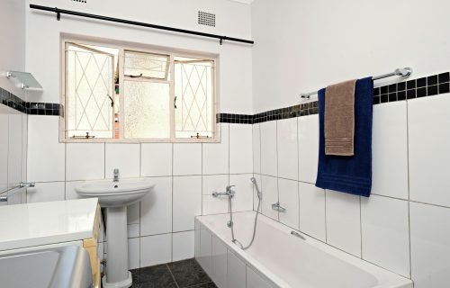 Bright minimalist bathroom with white tiles and natural light through window.