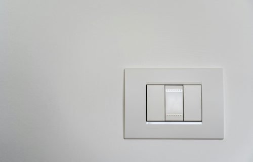 Close-up of a modern white light switch on a clean wall.